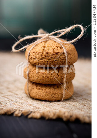 Oatmeal cookies tied with a rope on a wooden table. The concept of food for breakfast Oatmeal cookies tied with a rope on a wooden table. The concept of food for breakfast 112847434