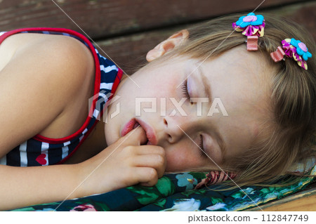 Portrait of sleeping pretty child girl who sucks her finger while sleeping. 112847749