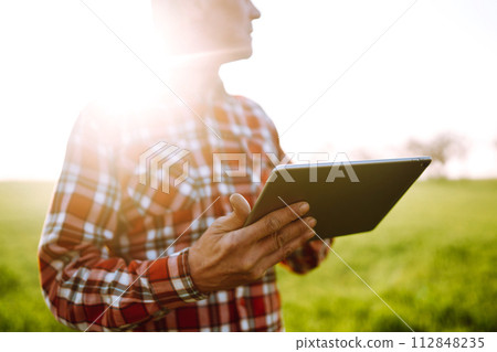 Farmer working with digital tablet in field at sunset. Checking wheat field. Agriculture concept. 112848235