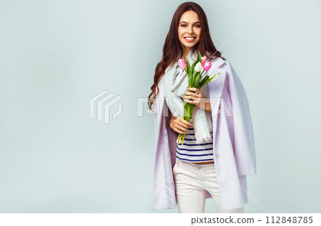 Fashion photo of beautiful woman with tulips in her hand. March 8. beautiful girl in stylish clothes Fashion photo of beautiful woman with tulips in her hand. March 8. beautiful girl in stylish clothes 112848785