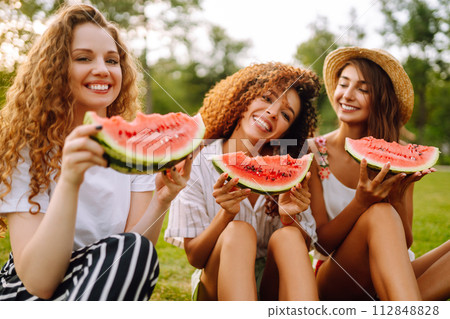 Three young woman have fun together and eating watermelon in hot summer day. 112848828