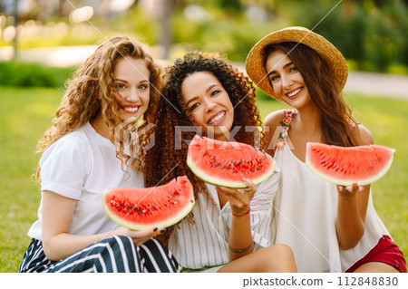 Three young woman have fun together and eating watermelon in hot summer day. 112848830