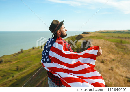 4th of July. American Flag.Patriotic holiday. Traveler with the flag of America. Beautiful sunset light. American style. 112849001