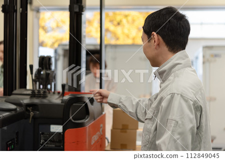 一名男工人在開始工作前檢查一輛四叉車。 112849045