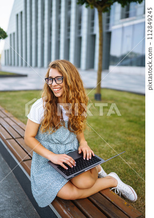 Woman working online on laptop computer outdoor. Business, blogging, freelance, education concept. 112849245