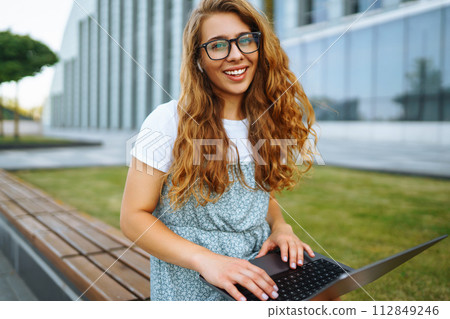 Woman working online on laptop computer outdoor. Business, blogging, freelance, education concept. 112849246