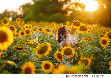 Beautiful woman posing in a field of sunflowers in a dress and hat. Fashion, lifestyle concept. Beautiful woman posing in a field of sunflowers in a dress and hat. Fashion, lifestyle concept. 112849509