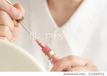 Woman's hand holding lip gloss Woman's hand holding lip gloss 112849532