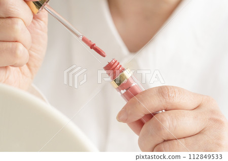 Woman's hand holding lip gloss Woman's hand holding lip gloss 112849533