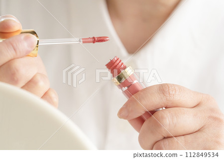 Woman's hand holding lip gloss 112849534