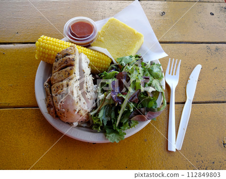 Herb chicken plate with nalo greens salad, corn on the cob, and corn beard 112849803