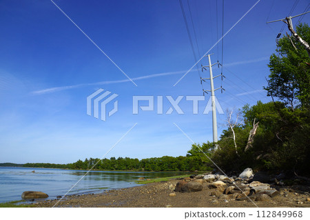 Rocky beach lined with trees on Cousins Island with Large Power line overhead Rocky beach lined with trees on Cousins Island with Large Power line overhead 112849968
