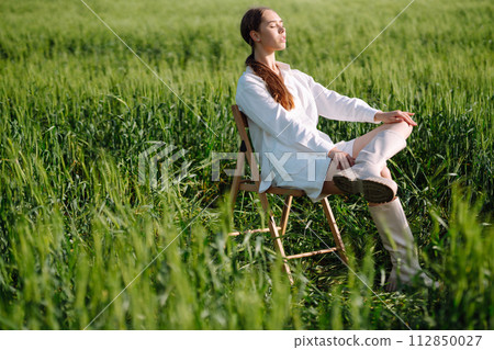 Young woman in white suit posing in green wheat field. Fashion and lifestyle concept. 112850027