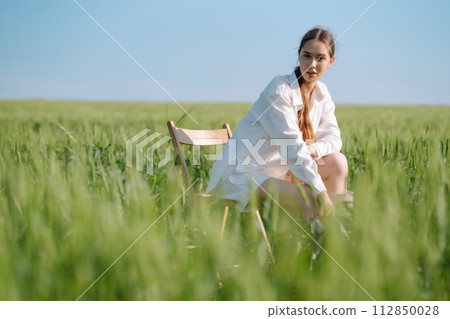 Young woman in white suit posing in green wheat field. Fashion and lifestyle concept. 112850028