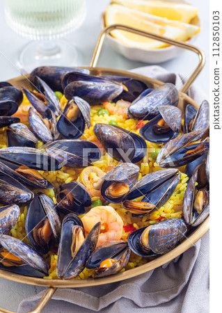Paella with mussels and shrimps in traditional plate, vertical, closeup 112850103