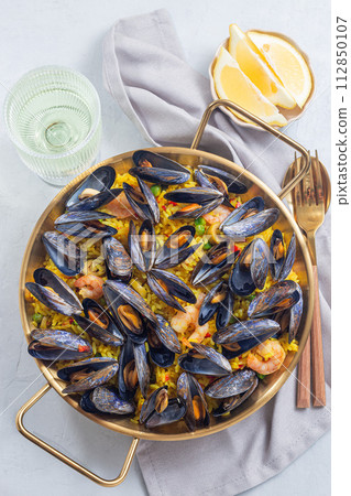 Seafood paella with mussels and shrimps in traditional plate, vertical, top view Seafood paella with mussels and shrimps in traditional plate, vertical, top view 112850107