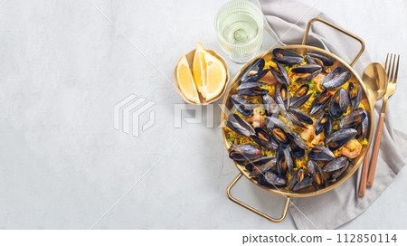 Seafood paella with mussels and shrimps in traditional plate, horizontal, top view, copy space 112850114