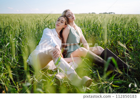 Two Beautiful woman in the green field. Nature, vacation, relax and lifestyle. Summer landscape. 112850183