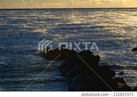 The morning sun shines on the misty sea surface of the Pacific Ocean on the Cretaceous reefs of Hiraiso Coast. 112851571