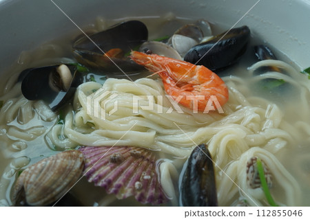 Kalguksu with seafood is made by boiling thin noodles with seafood, such as shrimp, octopus, and clam, in a baby clam broth. Kalguksu with seafood is made by boiling thin noodles with seafood, such as shrimp, octopus, and clam, in a baby clam broth. 112855046