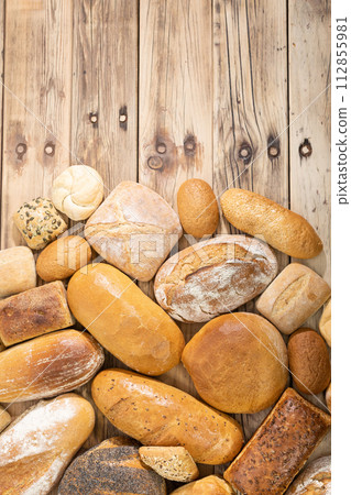 Many kinds and kinds of bread collected in one place on a wooden old shop counter as a decoration for a traditional bakery. View from above. Many kinds and kinds of bread collected in one place on a wooden old shop counter as a decoration for a traditional bakery. View from above. 112855981