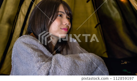 It's cold and a young woman wrapped in a blanket Camping image 112859197