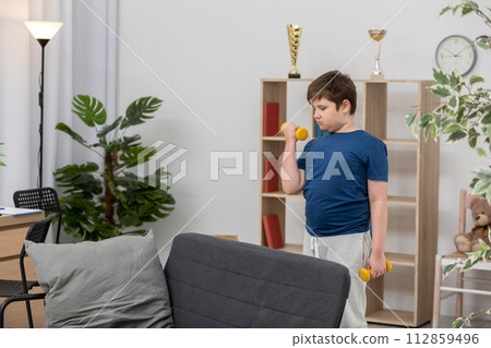 A young boy trains with dumbbells for health. A young boy trains with dumbbells for health. 112859496