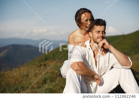 Man and woman in the mountains. Young couple in love at sunset. Woman in a blue dress. 112862246