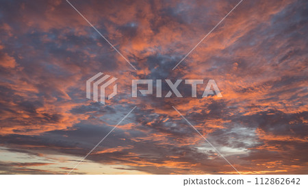 Dramatic sunset with vibrant clouds lit by a sun 112862642