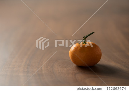 Small organic tangerine with stem on wood table Small organic tangerine with stem on wood table 112862674