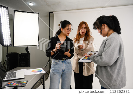 Production team and photographer working together in studio with camera and lighting equipment 112862881