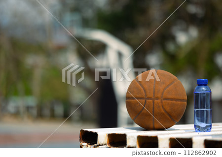 Basketball near a bottle of water on basketball court. Sport, training and competition concept Basketball near a bottle of water on basketball court. Sport, training and competition concept 112862902