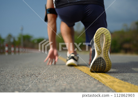Young sportsman in start position ready to run on the road. Sport, training and lifestyle concept 112862903