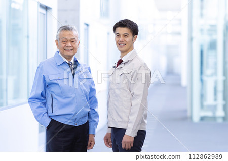 Two men in work clothes smiling 112862989