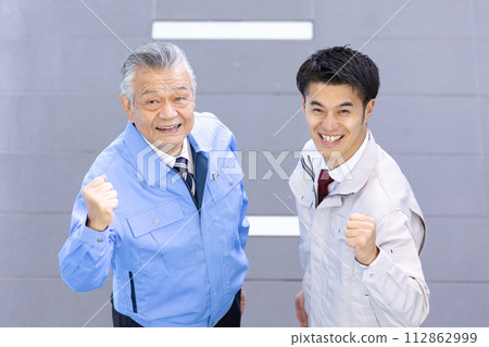 2 men in work clothes fist pump 2 men in work clothes fist pump 112862999