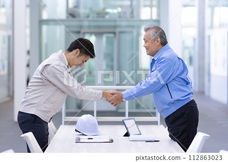 Man in work clothes Shaking hands 112863023
