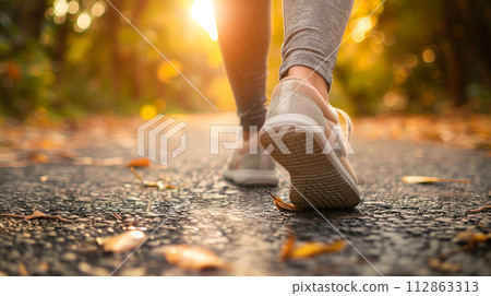 Feet of a woman walking on the autumn road 112863313