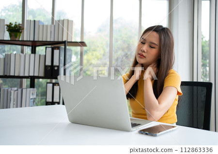 Beautiful young Asian businesswoman, shoulders and back pain during work long time on workplace. Body muscles stiff problem after long day work and overworked. Office syndrome and Healthcare concept. 112863336