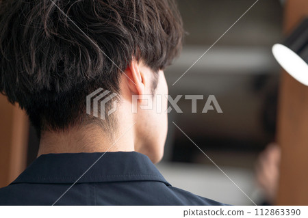 A man adjusting his hair while looking in the mirror A man adjusting his hair while looking in the mirror 112863390