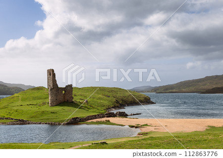 Ruins of Ardvreck Castle rising on a grassy peninsula, kissed by Loch Assynt waters 112863776