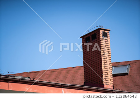 A tall chimney clinker brick built on the roof of a public building. 112864548