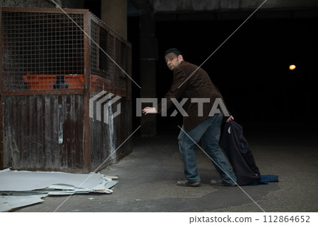 A middle-aged homeless man has found garbage cans and is heading towards him. A middle-aged homeless man has found garbage cans and is heading towards him. 112864652