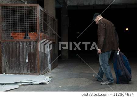 A middle-aged homeless man has found garbage cans and is heading towards him. A middle-aged homeless man has found garbage cans and is heading towards him. 112864654