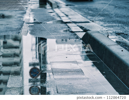 Traffic signs reflected in puddles on the sidewalk on a rainy day 112864720