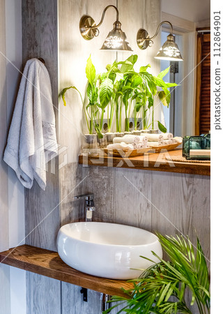 Bathroom design in loft or boho style with sink, towels and Spathiphyllum flowers in vase 112864901