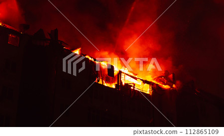 Burning house is engulfed in flames. Fire blazing in apartment building. Firefighters extinguish with water. Burning house is engulfed in flames. Fire blazing in apartment building. Firefighters extinguish with water. 112865109