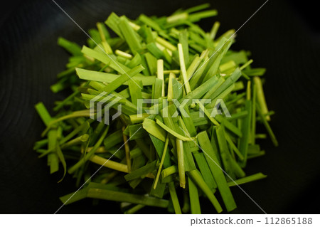 Fresh chives in a black bowl on wooden table, close up Fresh chives in a black bowl on wooden table, close up 112865188