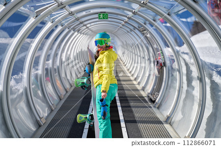 Snowboarder on Covered Escalator to Slopes 112866071
