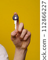 Close-up image of a man hand holding home key with isolated yellow background and copy space. Perfect for conveying concepts of homeownership, real estate, property, and security. High quality photo 112866227