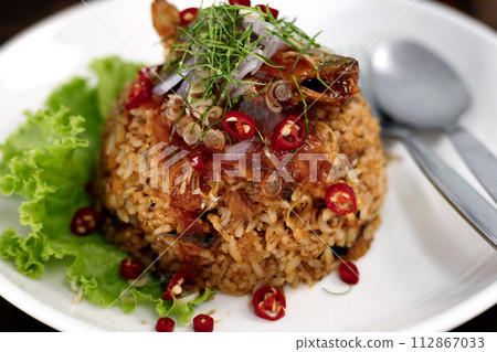 Thai food, Fried jasmine rice with canned fish mackerel in tomato sauce, topped with red chili, red onion, lettuce and kaffir lime leaves. Thai food, Fried jasmine rice with canned fish mackerel in tomato sauce, topped with red chili, red onion, lettuce and kaffir lime leaves. 112867033